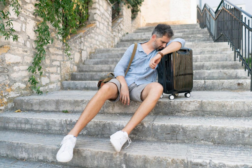 tired man on steps with luggage